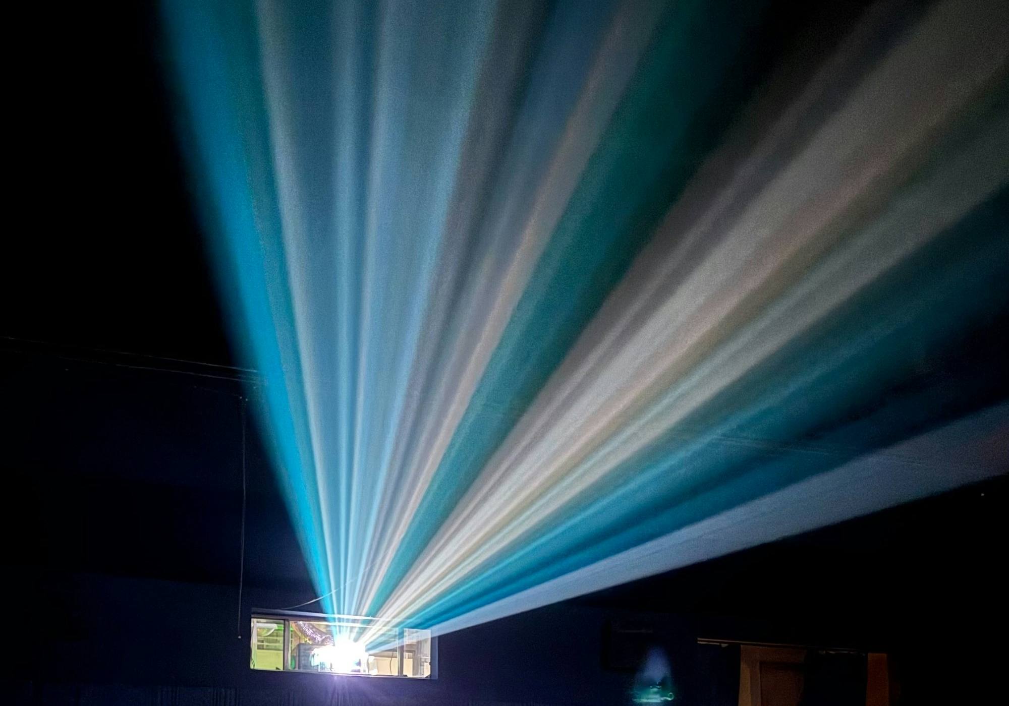 Projector light fanning out in beams across a dark, empty cinema
