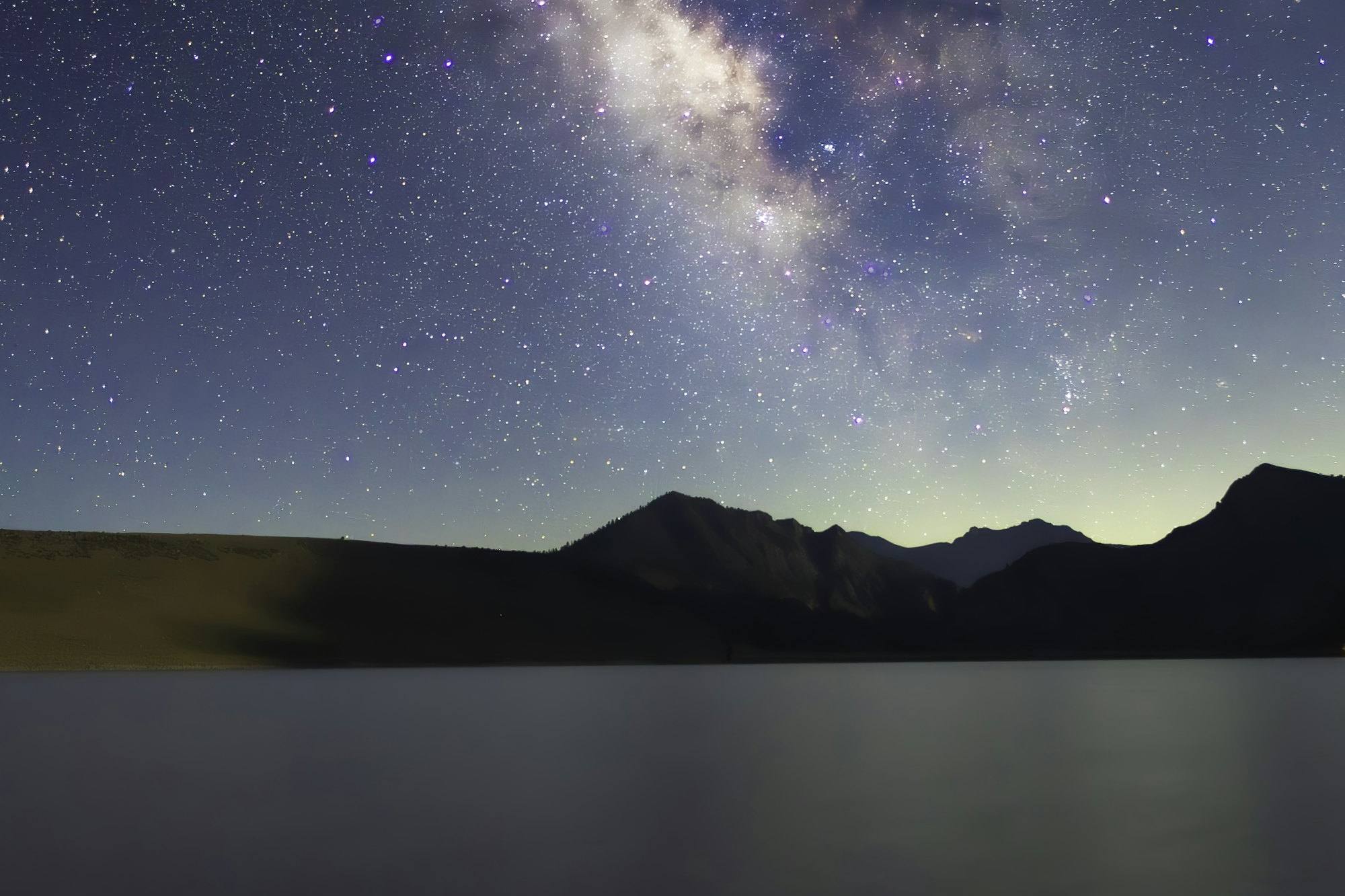 The Milky Way reflected in a still mountain lake at night