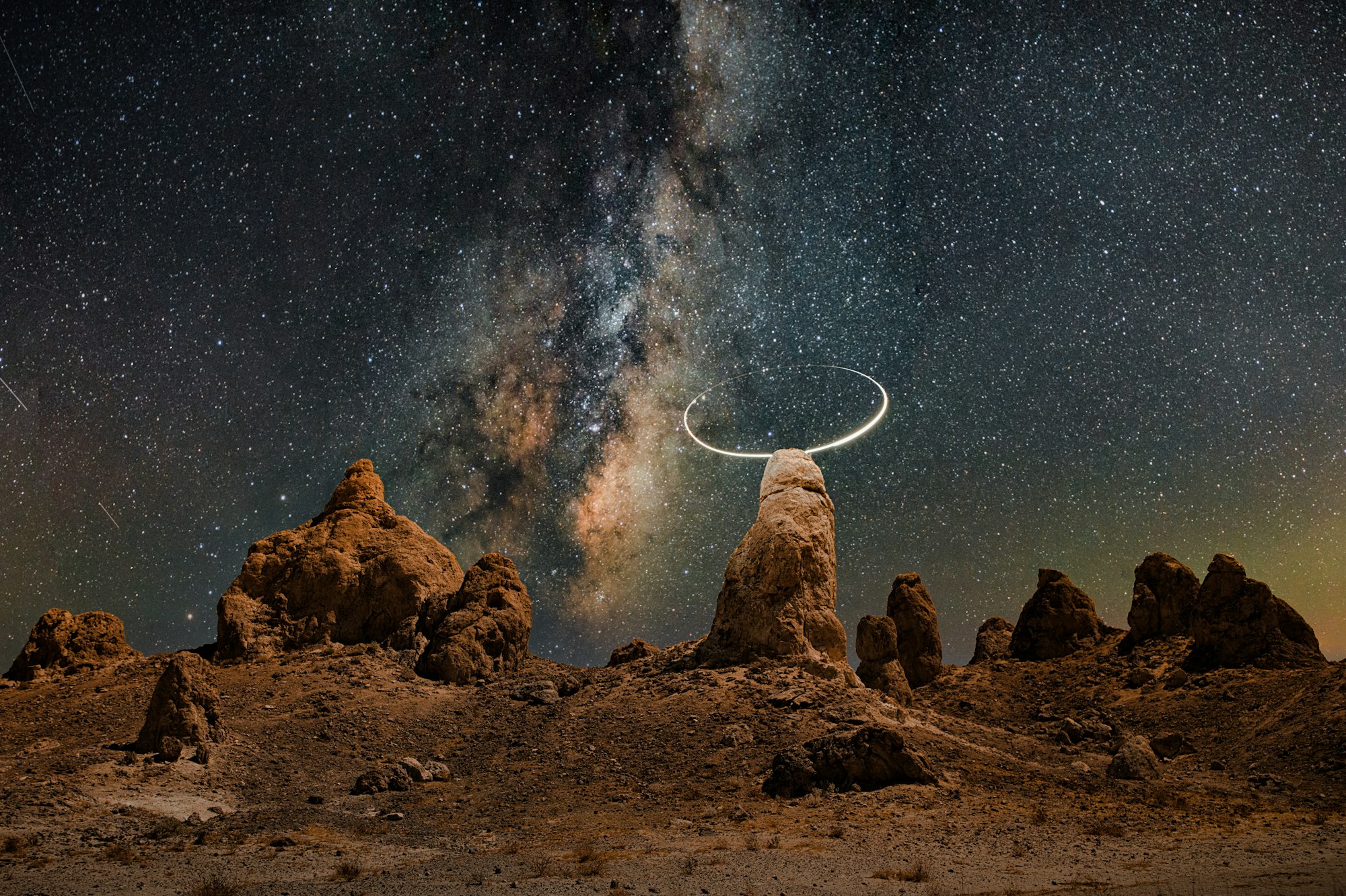 Stone pinnacles in a desert under the Milky Way, one ringed by a circle of light